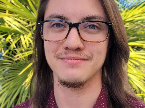 A headshot of Leo wearing a burgundy spotted polo