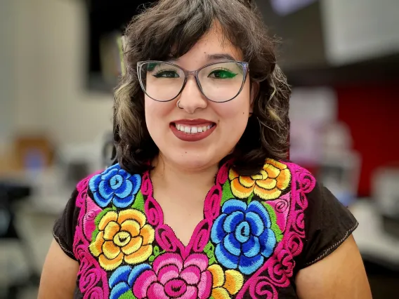 A portrait of Naty wearing a colorful embroidered shirt